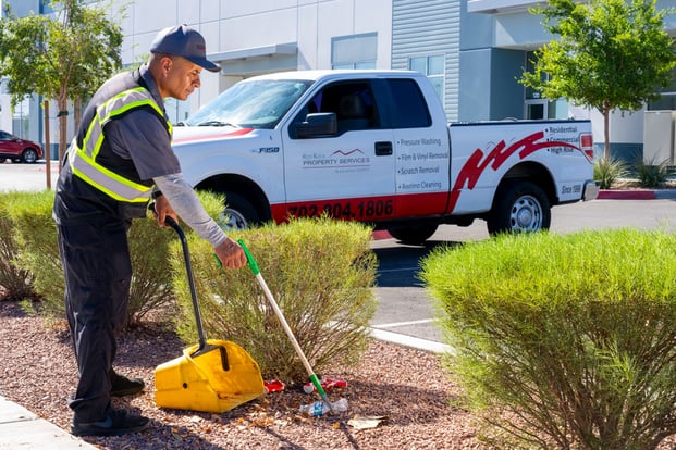 Red Rock property service professional removing trash and other debris outside of a retail outlet